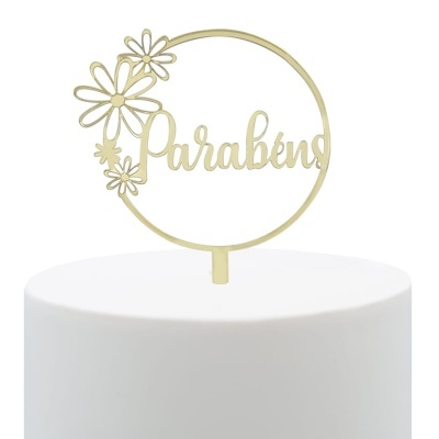 Topo de bolo dourado com flores e palavra Parabéns em bolo branco