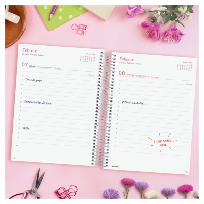 Agenda aberta nas datas 07 e 08 de fevereiro com anotações manuscritas, flores e material de escritório em fundo rosa