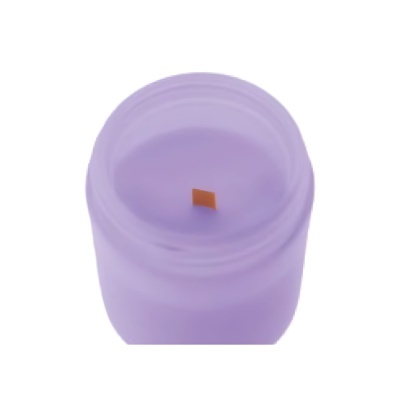 Vela aromática lilás em copo de vidro lilás com pavio castanho.