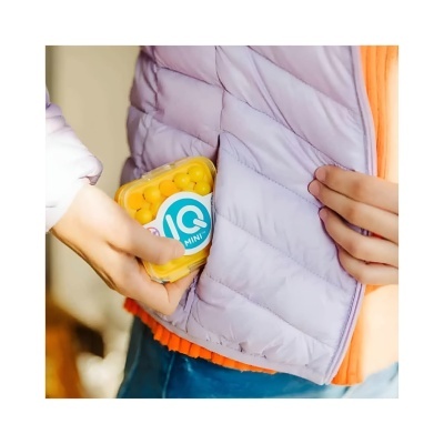 Pessoa a colocar caixa IQ MINI no bolso de casaco lilás acolchoado