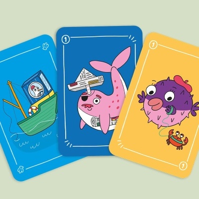 Três cartas de jogo ilustradas com desenhos coloridos de um navio, uma baleia e um peixe com caranguejo.