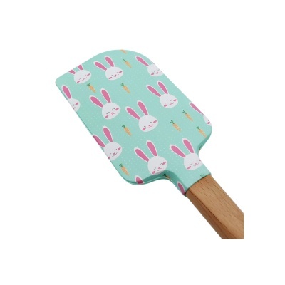 Espátula de silicone azul com padrão de coelhos e cenouras e cabo de madeira