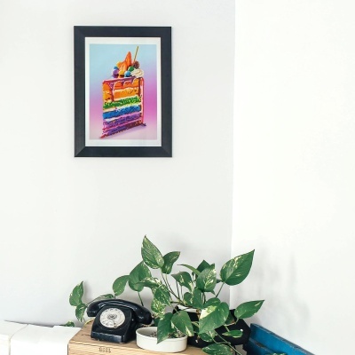 quadro de fatia de bolo colorido na parede e telefone antigo com planta ao lado