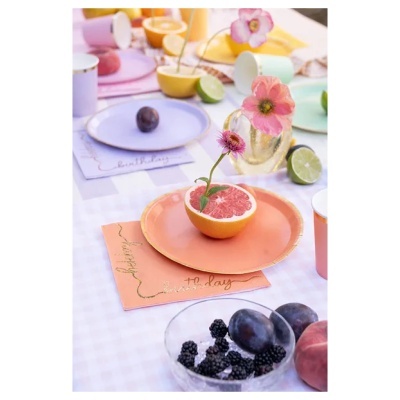 Mesa com pratos pastel, flores em toranja, frutas frescas e guardanapos com texto special birthday
