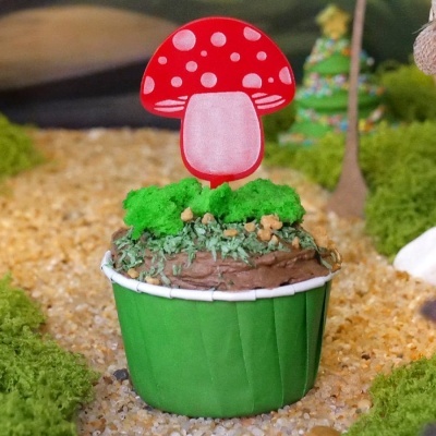 Cupcake decorado com cobertura de chocolate e etiqueta de papel de cogumelo vermelho.