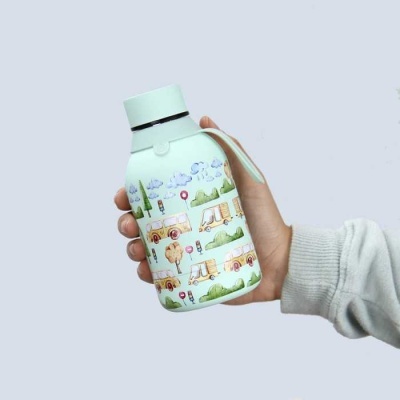 Frasco branco decorado com ilustrações de carrinhas e autocaravanas, tampa verde clara, segurado por mão com manga cinza