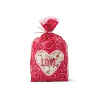 Saco vermelho com corações e janela em forma de coração mostrando pipocas com texto LOVE