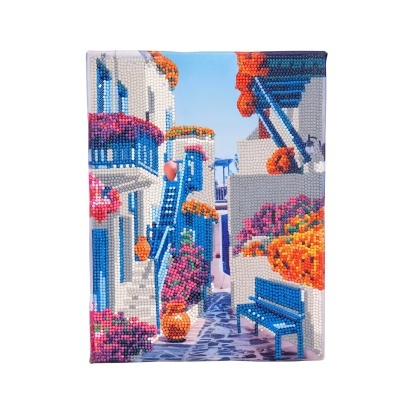 Quadro decorativo com imagem bordada de uma rua de vila mediterrânica com casas brancas e detalhes azuis