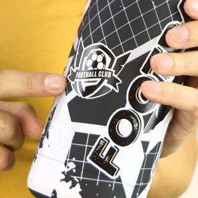 Garrafa desportiva com design futebolístico preto e branco segurada por mãos