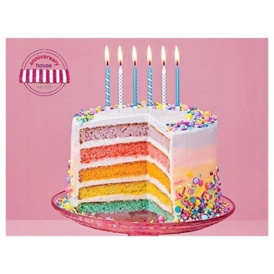 Bolo de aniversário colorido com velas acesas em prato de vidro rosa