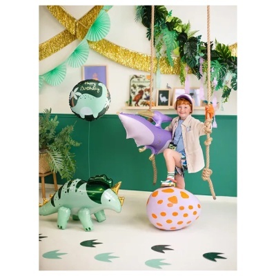 Criança em balanço com balões de dinossauros e decoração festiva