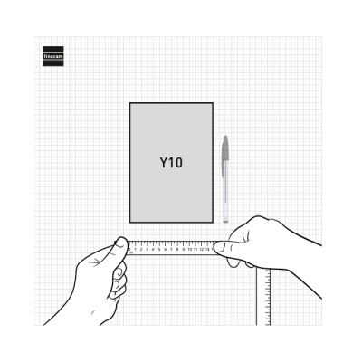 Bloco de notas Y10, caneta, régua e mãos a medir em superfície quadriculada