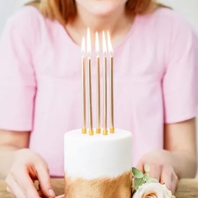 Bolo pequeno branco e dourado com velas acesas e rosa decorativa