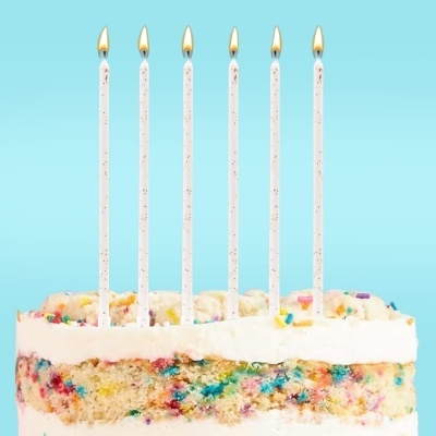 Bolo colorido com velas acesas em fundo azul.