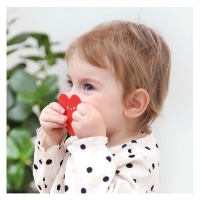 Bebé a segurar brinquedo vermelho em forma de coração.
