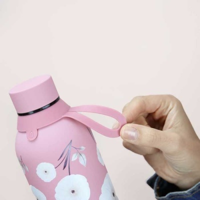 Garrafa térmica rosa com flores brancas segurada por uma mão