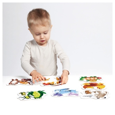 Criança a brincar com puzzle de animais sobre mesa branca