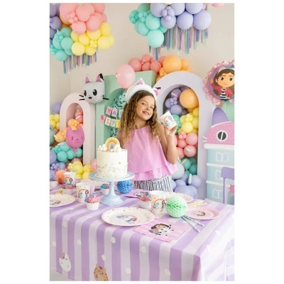 Festa infantil com decoração temática de gatos, balões coloridos, bolo branco e toalha de mesa lilás com riscas e estampas de gatos.