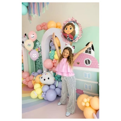Criança com roupa rosa e riscas em festa com decoração de balões coloridos pastel
