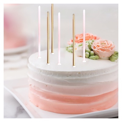 Bolo branco e rosa decorado com flores e velas finas douradas e brancas