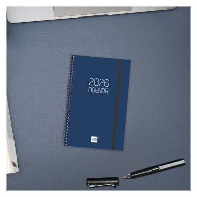 Agenda 2026 azul com espiral e caneta preta sobre mesa azul