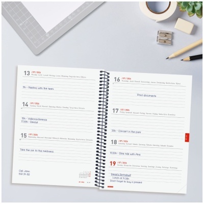 Agenda semanal aberta com acessórios de escritório sobre mesa cinzenta