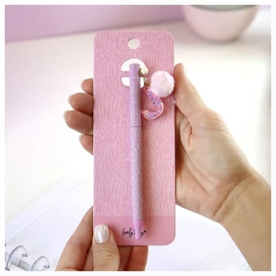 Caneta rosa com chaveiro da letra J e bola de pelo, em embalagem rosa com padrão de letras