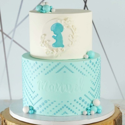 Bolo dois andares azul e branco com decoração de esferas e padrão pontilhado.