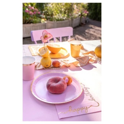 Mesa de jardim decorada com pratos, copos e frutas em tons de rosa e dourado.