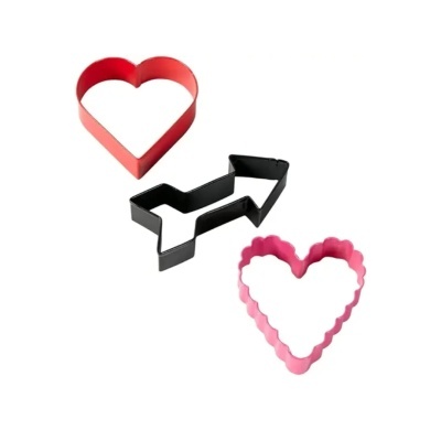 Três cortadores de biscoitos coloridos em metal sobre fundo branco