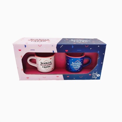 Conjunto de duas canecas em caixa, branca e azul, com textos humorísticos.