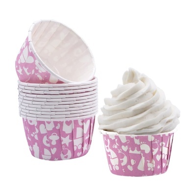 Forminhas para cupcakes rosas com padrões brancos e uma com cobertura branca.