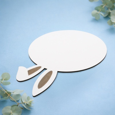 Forma branca oval com orelhas de coelho em cartão sobre fundo azul e folhas verdes