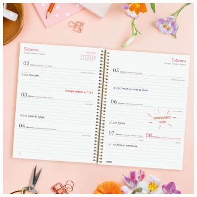 Agenda semanal aberta com anotações e flores ao redor