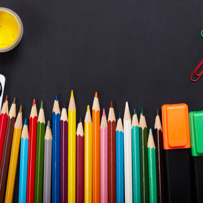 Materiais de arte e escritório sobre mesa preta.