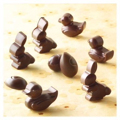 Figuras de chocolate em forma de coelhos e patos sobre superfície clara com flores