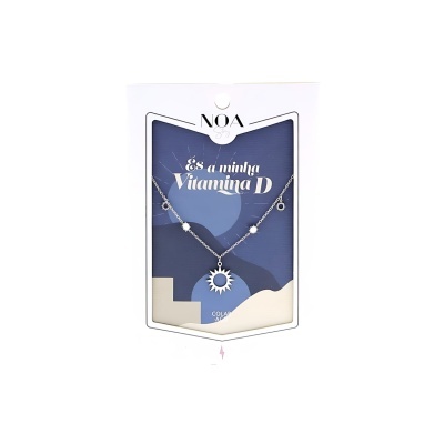 Colar prateado com pendente em forma de sol numa embalagem com texto 'És a minha Vitamina D'