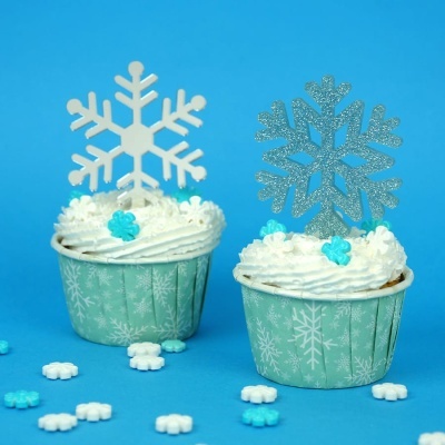 Dois cupcakes decorados com flocos de neve em forminhas verdes com padrão de flocos