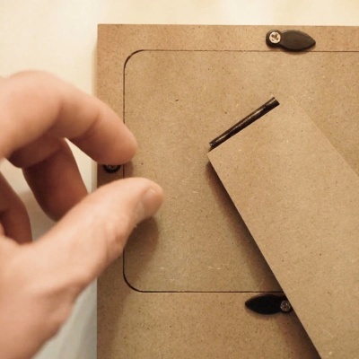 Mão a segurar suporte de cartão castanho com ferragens pretas em moldura