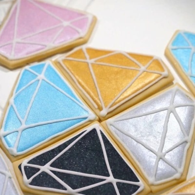 Bolachas decoradas em forma de diamante com glacê colorido e linhas geométricas
