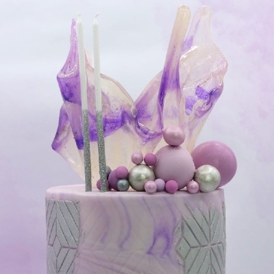 Bolo decorado em tons de lavanda e roxo com velas e decoração translúcida