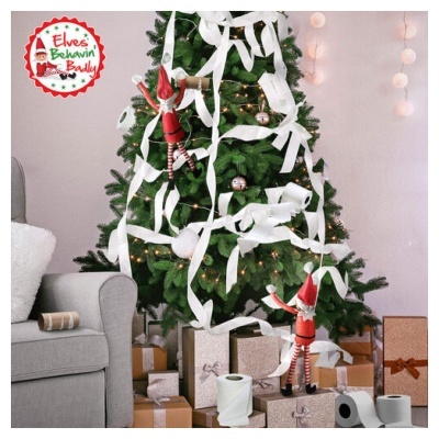 Árvore de Natal decorada com luzes e papel higiénico, presentes e elfos em ambiente de sala com sofá.
