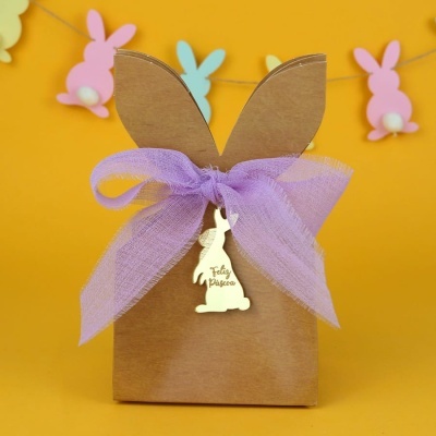 Embalagem de papel castanho em forma de coelho com fita lilás e pendente dourado Feliz Páscoa