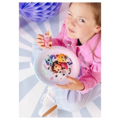 Criança com casaco rosa segurando um prato de papel com desenhos animados e a comer um donut cor de rosa