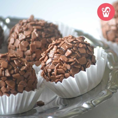 Trufas de chocolate em forminhas brancas sobre prato prateado