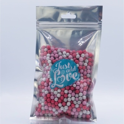 Saco transparente com esferas coloridas rosa, vermelho e branco, com etiqueta 'Just add Love'