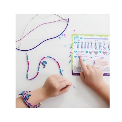 Mãos a fazer pulseiras com fios coloridos e contas e instruções impressas.