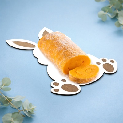 Rolo de bolo amarelo em prato de coelho com fundo azul e folhas verdes