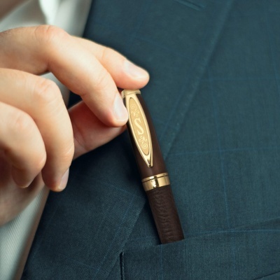 Caneta castanha com detalhes dourados no bolso de casaco azul escuro