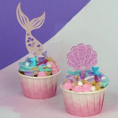 Dois cupcakes com decoração temática de sereia e concha em copos de papel rosa